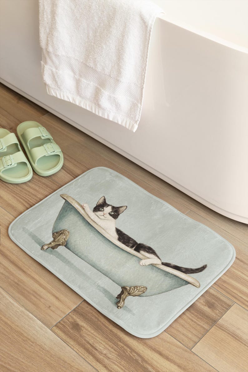 Peut inclure: Un tapis de bain bleu clair avec un chat noir et blanc dans une baignoire. Le chat est allong&eacute; dans la baignoire, la t&ecirc;te pos&eacute;e sur le bord. La baignoire a des pieds dor&eacute;s.