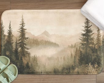 May include: A watercolor-style bath mat featuring a misty forest scene with tall pine trees and a mountain range in the background. The colors are muted greens, browns, and grays.
