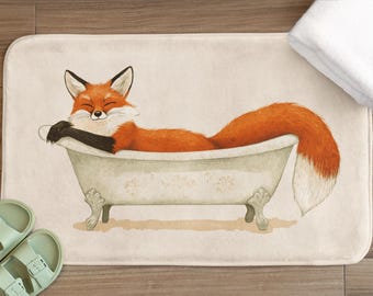 May include: A cream-colored bath mat with a cartoon illustration of a red fox relaxing in a white bathtub. The fox is smiling and has its eyes closed.