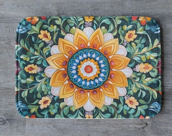 May include: Rectangular floral patterned mat featuring a large, central flower design with yellow, orange, white, and blue petals. The mat has a dark green background with smaller yellow flowers and green leaves.