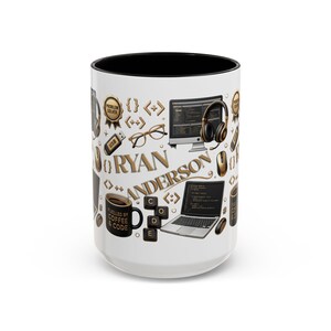 May include: A white ceramic mug with a black interior featuring a repeating pattern of computer-related icons including a laptop, monitor, headphones, glasses, USB drive, and keyboard keys. The name RYAN ANDERSON is printed in gold lettering.