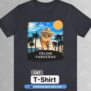 May include: A dark blue t-shirt featuring a graphic of a cat wearing sunglasses and a hat on a beach with palm trees. The text "Feline Fabulous" is printed below the cat. The text "CAT T-Shirt" is printed below the graphic. The text "by catksydesigns.etsy.com" is printed below the text "CAT T-Shirt".