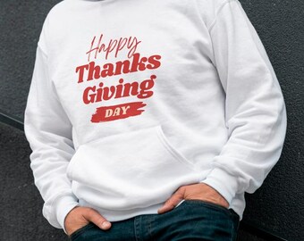 May include: White hooded sweatshirt with a front pocket, featuring the text "Happy Thanksgiving Day" in red script. The sweatshirt is worn with blue jeans.