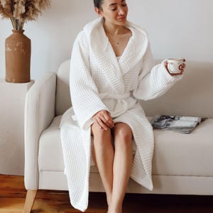 Model sitting on a sofa in the white waffle housecoat with a coffee cup and magazine – elegant cotton waffle housecoat