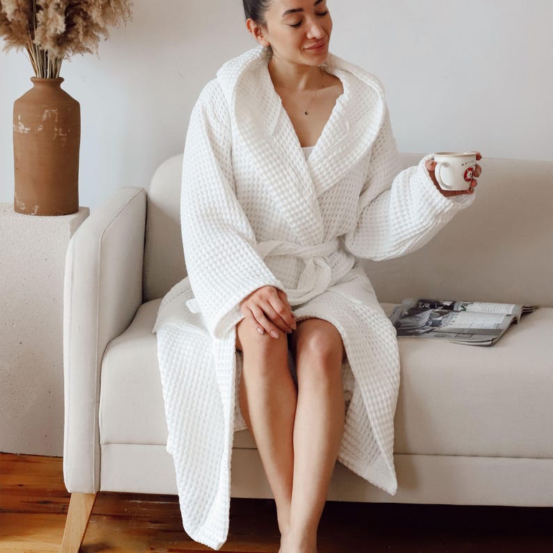 Model sitting on a sofa in the white waffle housecoat with a coffee cup and magazine – elegant cotton waffle housecoat