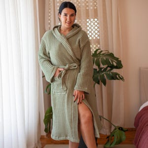 Model in the sage green waffle housecoat in a bedroom, belt tied – elegant cotton waffle housecoat