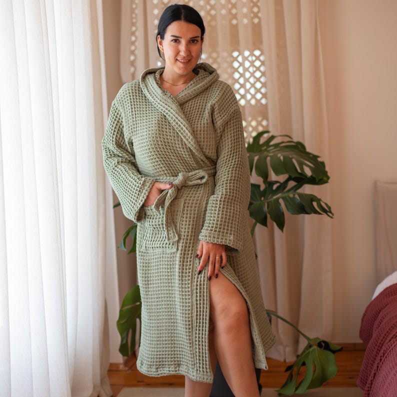 Model in the sage green waffle housecoat in a bedroom, belt tied – elegant cotton waffle housecoat