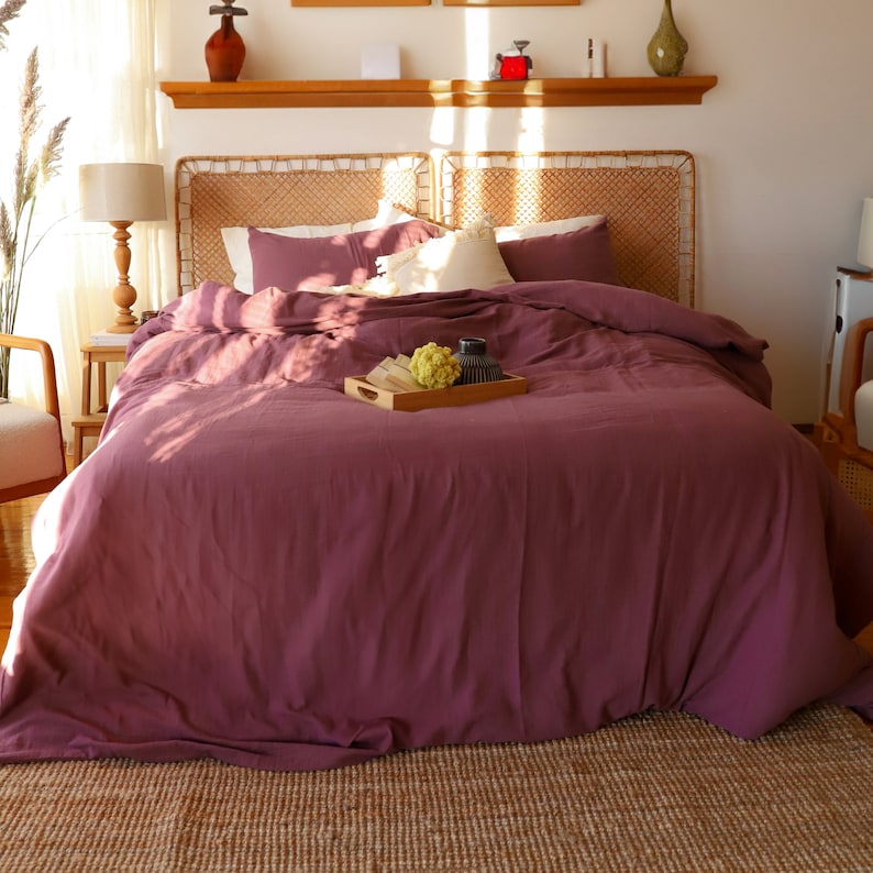 Burgundy muslin duvet cover set with two matching pillowcases, folded and stacked on white background