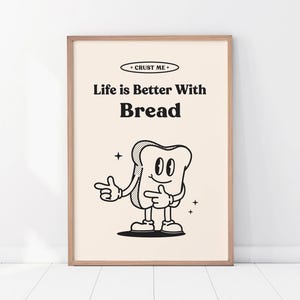 Op de afbeelding: Een zwart-witte illustratie van een glimlachende snee brood met de tekst "CRUST ME" en "Life is Better With Bread" op een beige achtergrond.