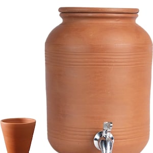 Puede incluir: Un enfriador de agua de terracota con un grifo plateado y una taza de beber de terracota a juego. El enfriador tiene una tapa y está diseñado para mantener el agua fría.