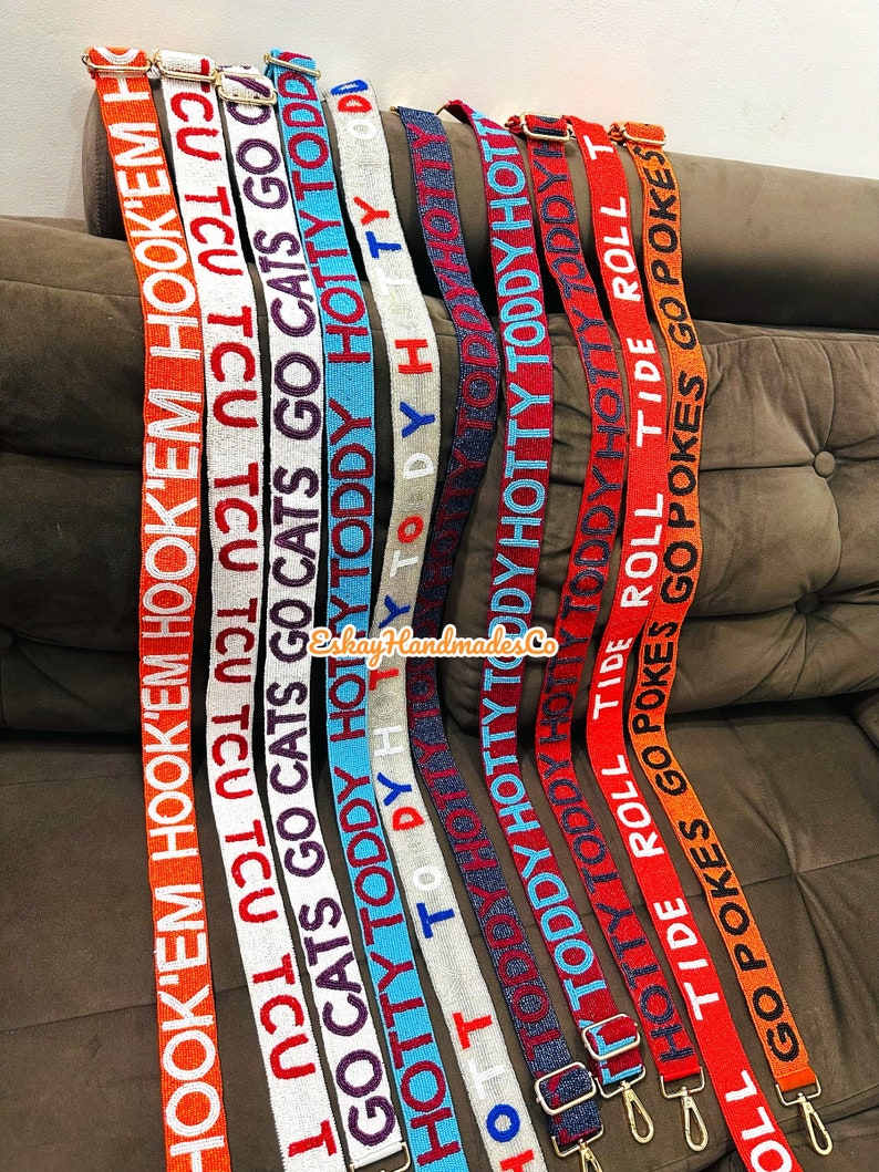 May include: A collection of colourful woven straps with various text printed on them, including "HOOK'EM", "TCU", "GO CATS", "HOTTY TODDY", "TIDE ROLL", and "GO POKES".