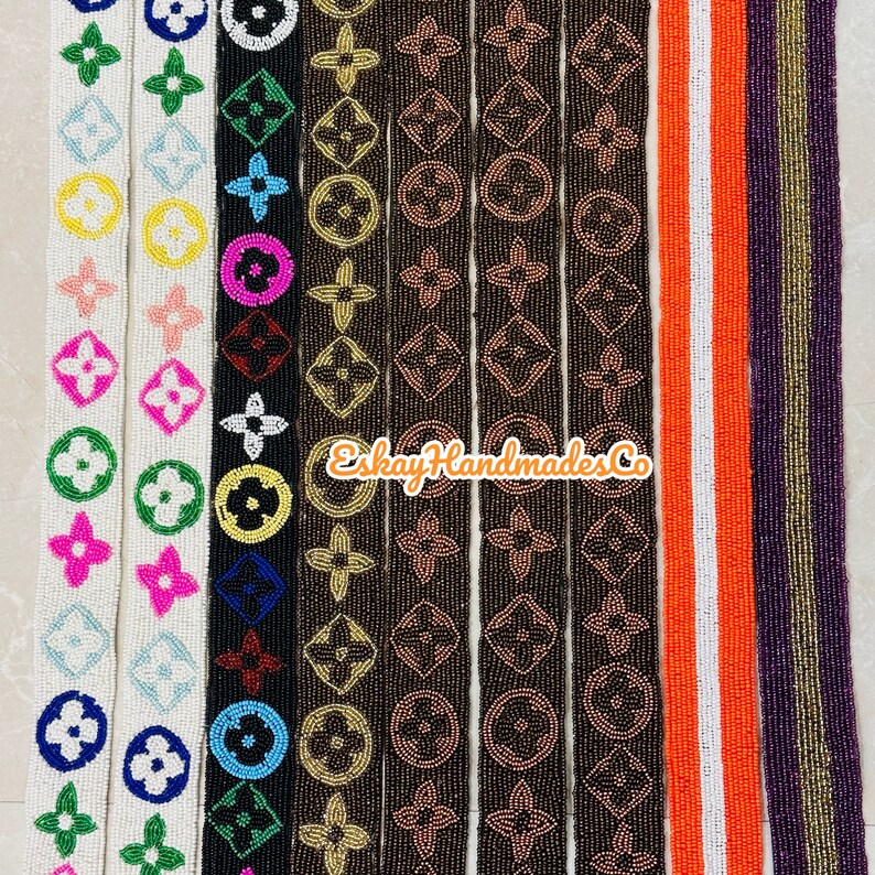 May include: Assortment of beaded trim featuring a repeating pattern of the Louis Vuitton logo in various colours, including white, black, brown, and orange. The trim is approximately 2.5 cm wide and is perfect for adding a touch of luxury to any project.