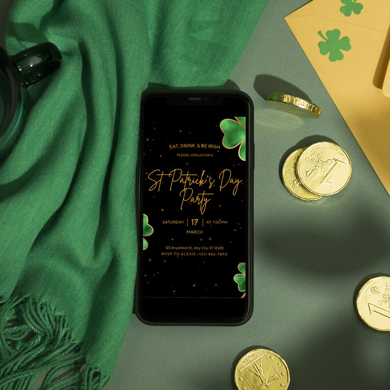 May include: A smartphone displays a St. Patrick's Day party invitation with gold text and shamrock accents. The phone rests on a green surface with a green scarf, gold coins, and a shamrock-decorated envelope.