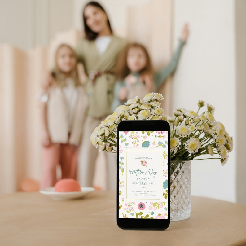 May include: A floral phone screen displaying a Mother's Day brunch invitation with the text "Mother's Day Brunch, Sunday, May 12, 12 pm".