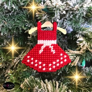 May include: Red and white Christmas ornament shaped like a dress with white polka dots. The ornament is hanging on a Christmas tree.