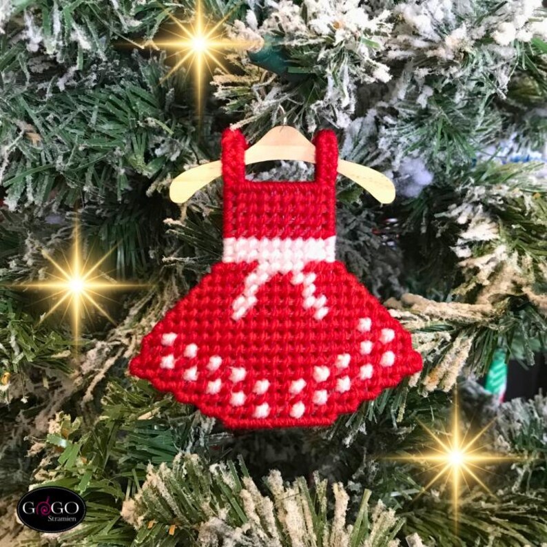 May include: Red and white Christmas ornament shaped like a dress with white polka dots. The ornament is hanging on a Christmas tree.