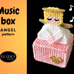 May include: A pink and white music box with a crocheted angel on top. The angel has a gold halo and wings. The music box has a heart-shaped design on the front.