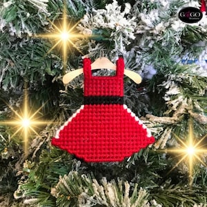 May include: Red and white Christmas ornament shaped like a dress with a black belt. The ornament is hanging on a Christmas tree.