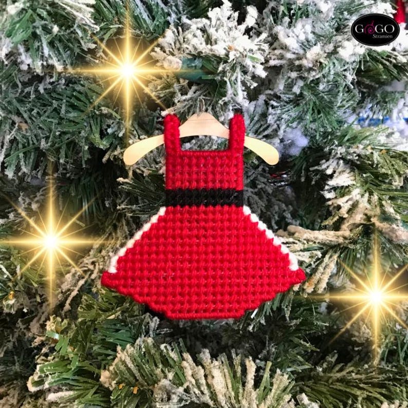 May include: Red and white Christmas ornament shaped like a dress with a black belt. The ornament is hanging on a Christmas tree.