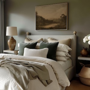 Puede incluir: Una cama con un edred&oacute;n blanco y una manta de color verde y marr&oacute;n. La cabecera de la cama es de tela beige y marco de madera marr&oacute;n. Hay varias almohadas en la cama, incluyendo una almohada de terciopelo verde, una almohada beige y una almohada blanca. La cama est&aacute; en una habitaci&oacute;n con una pared verde y una pintura en la pared.