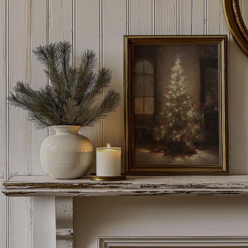 May include: A white ceramic vase with a green pine sprig arrangement sits on a white mantel with a framed picture of a Christmas tree and a white candle on a gold metal plate.