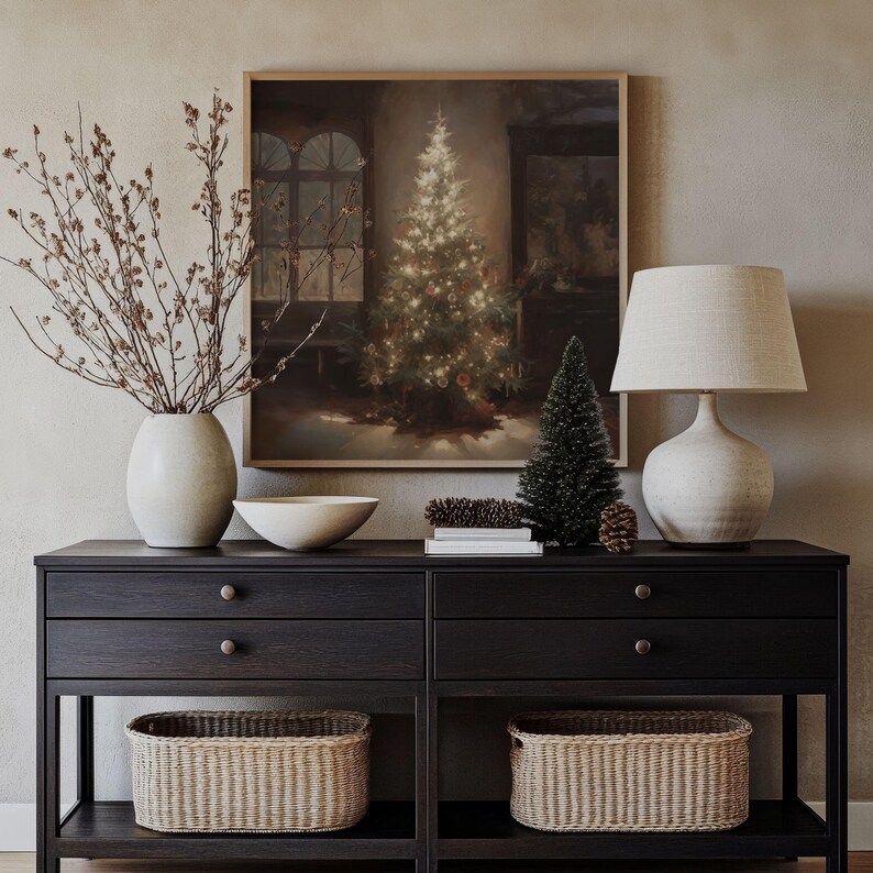 May include: A black wooden console table with two drawers and two open shelves. The table has a framed print of a Christmas tree with lights, a white ceramic lamp with a linen shade, a bowl, and two woven baskets on the shelves.