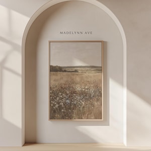 May include: A framed landscape print featuring a field of wildflowers in muted tones of beige, brown, and white. The artwork is set against a neutral background and framed in a light wood. The text "MADELYNN AVE" is above the frame.