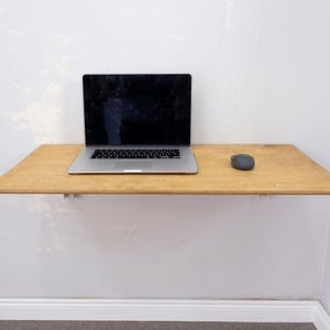 Here is Wall Mounted Foldable Home Office Desk Table! This Fold Down Small Space Saving Laptop Desk in the home office, balcony or kitchen perfectly complements the cozy atmosphere, offering a personalized touch to the workspace.