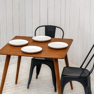 Here is Square Walnut Wooden Dining Room Table! This Narrow Space Dine Table Kitchen in the dining room perfectly complements and change the cozy small home atmosphere, offering a personalized touch to the kitchen.