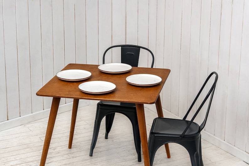 Here is Square Walnut Wooden Dining Room Table! This Narrow Space Dine Table Kitchen in the dining room perfectly complements and change the cozy small home atmosphere, offering a personalized touch to the kitchen.