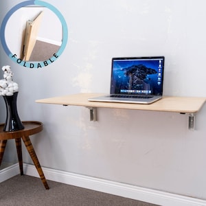 Here is Wall Mounted Foldable Home Office Desk Table! This Fold Down Small Space Saving Laptop Desk in the home office, balcony or kitchen perfectly complements the cozy atmosphere, offering a personalized touch to the workspace.