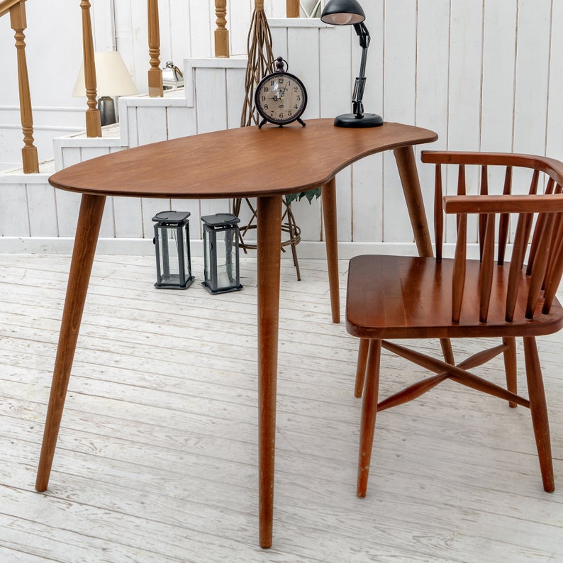 Enhance your workspace with this elegant ellipse desk table, designed to bring style and function together. Ideal as a wood laptop table or small writing desk, its boomerang desk table silhouette adds a midcentury charm. Crafted from quality walnut, this midcentury wood desk doubles as a mid century table and a practical computer desk table. Whether used as a home office desk, modern wooden desk, or walnut writing desk, it fits seamlessly into any interior.
