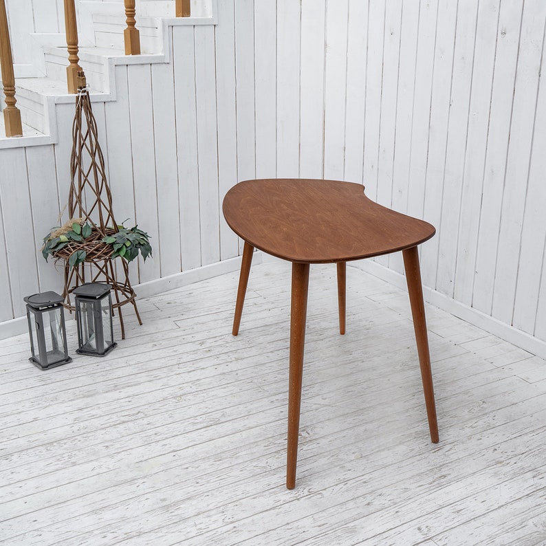 Enhance your workspace with this elegant ellipse desk table, designed to bring style and function together. Ideal as a wood laptop table or small writing desk, its boomerang desk table silhouette adds a midcentury charm. Crafted from quality walnut, this midcentury wood desk doubles as a mid century table and a practical computer desk table. Whether used as a home office desk, modern wooden desk, or walnut writing desk, it fits seamlessly into any interior.