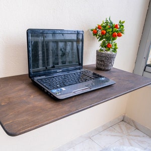 Here is Wall Mounted Foldable Home Office Desk Table! This Fold Down Small Space Saving Laptop Desk in the home office, balcony or kitchen perfectly complements the cozy atmosphere, offering a personalized touch to the workspace.