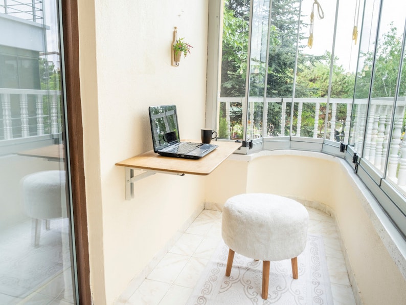 Here is Wall Mounted Foldable Home Office Desk Table! This Fold Down Small Space Saving Laptop Desk in the home office, balcony or kitchen perfectly complements the cozy atmosphere, offering a personalized touch to the workspace.