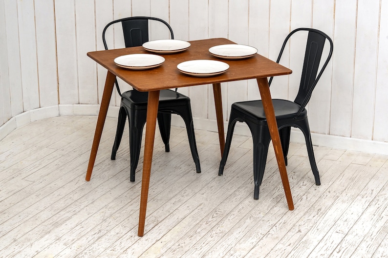 Here is Square Walnut Wooden Dining Room Table! This Narrow Space Dine Table Kitchen in the dining room perfectly complements and change the cozy small home atmosphere, offering a personalized touch to the kitchen.