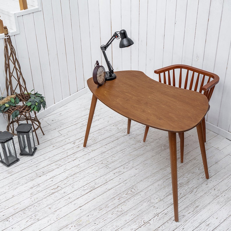 Enhance your workspace with this elegant ellipse desk table, designed to bring style and function together. Ideal as a wood laptop table or small writing desk, its boomerang desk table silhouette adds a midcentury charm. Crafted from quality walnut, this midcentury wood desk doubles as a mid century table and a practical computer desk table. Whether used as a home office desk, modern wooden desk, or walnut writing desk, it fits seamlessly into any interior.
