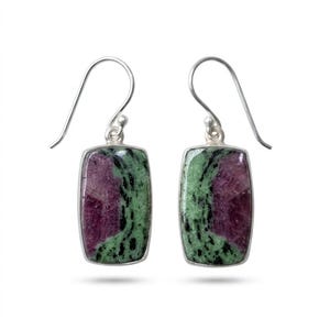May include: A pair of rectangular drop earrings featuring polished ruby zoisite stones set in silver bezels. Each stone displays a distinct pattern of deep magenta and vibrant green with black inclusions, suspended from simple silver ear wires.