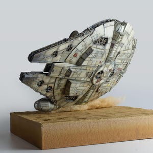 May include: A detailed model of the Millennium Falcon spacecraft, a Corellian YT-1300f light freighter, is depicted in flight. The model is primarily off-white with gray and red accents, mounted on a tan base, with a dust effect.