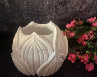 May include: White ceramic planter shaped like a lotus flower with a textured surface. The planter is ideal for small plants or succulents.