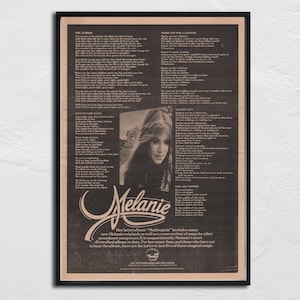 Può includere: Un poster vintage incorniciato con un ritratto della cantante Melanie, con testi di canzoni e informazioni sull'album. Il poster ha una cornice nera e uno sfondo color seppia, con il nome della cantante in una scrittura stilizzata.