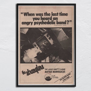 May include: A black and white vintage advertisement for the band The Stranglers. The ad features a photo of the band members and the text "When was the last time you heard an angry psychedelic band?" The ad also includes the album title "Rattus Norvegicus" and the text "First 10,000 include a free single."