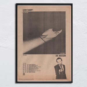 May include: A black and white poster advertising a concert by Joe Jackson. The poster features a photo of a shoe and the text "Look Sharp!" and "Joe Jackson". The poster also includes a list of tour dates.