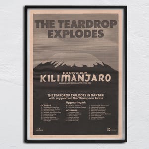 Può includere: Un poster vintage incorniciato per l'album "Kilimanjaro" dei The Teardrop Explodes. Il poster presenta il nome della band e il titolo dell'album in grassetto, con una grafica di montagna. Elenca anche le date del tour e il gruppo di supporto, The Thompson Twins.