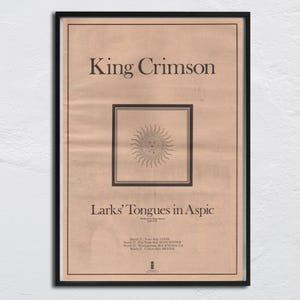 May include: Framed vintage poster for King Crimson's album "Larks' Tongues in Aspic." The poster features the band's name at the top, the album title, and a sun illustration. The poster is framed in a black frame.