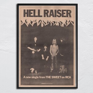 May include: Framed vintage poster for the song "Hell Raiser" by The Sweet. The black and white image features the band members and the text "A new single from THE SWEET on RCA". The poster has a black frame.