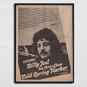 Può includere: Una pubblicità vintage incorniciata per il primo album di Billy Joel, "Cold Spring Harbor". L'immagine in bianco e nero presenta un ritratto di Billy Joel con testo promozionale. Il poster è esposto in una cornice nera.