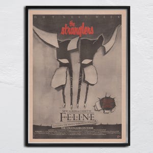 May include: A black and white poster advertising a new album and cassette by The Stranglers, titled "Feline". The poster features a stylized image of a cat's head with claws, and the text "The Stranglers on Tour" is printed at the bottom.