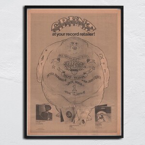 Peut inclure: An old framed advertisement for the band Jefferson Airplane. The poster features a cartoon figure and the text "GRUNT at your record retailer!". The artwork is in black and white and includes the band's name and members.