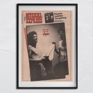 Puede incluir: Una foto en blanco y negro de la portada de una revista que presenta a un hombre con el torso desnudo y a un hombre con camisa. La revista se llama "Musical Express" y el titular es "Pistols Jubilee Thrashing Pics & Eye Witness Report".